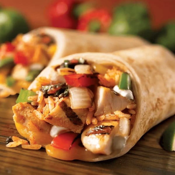 Two chicken burritos filled with rice, grilled chicken, onions, and bell peppers on a wooden surface.